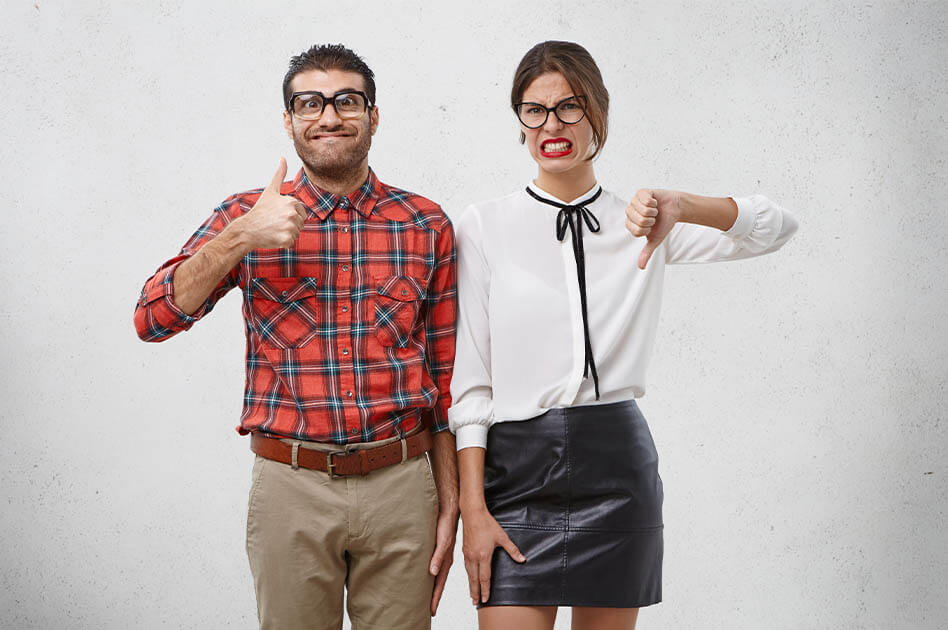 Egymás mellett álló férfi és nő, a férfi mosolyog és hüvelykujját felfelé mutatja, a nő grimaszol és hüvelykujját lefelé mutatja.